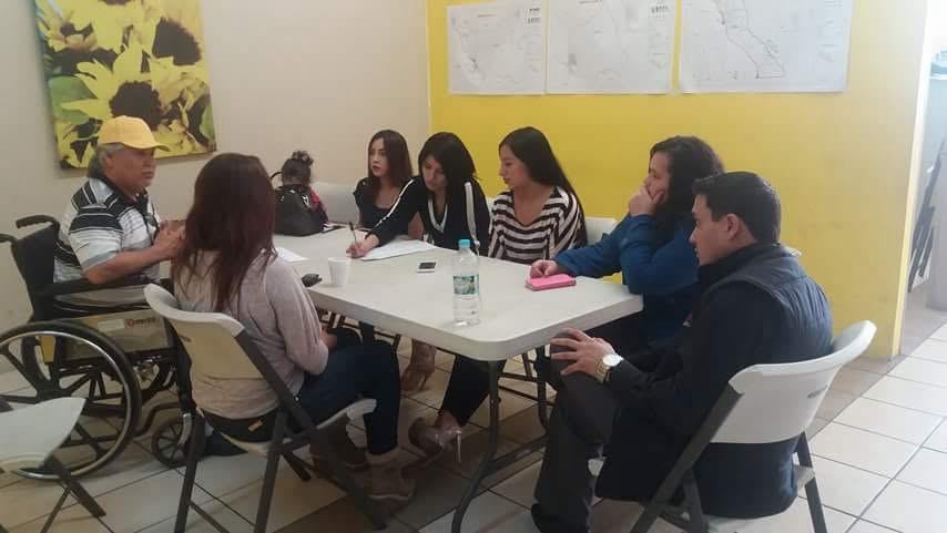 Reunión de trabajo con mapas y planos zonales colgados en la pared.