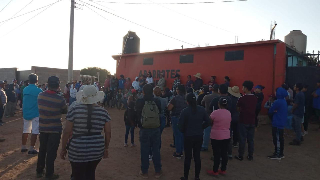 Reunión con vecinos frente a una tienda de abarrotes en una colonia sin pavimentar.